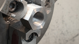 Image of hex stock being tapped with assistance of engine lathe for centering.